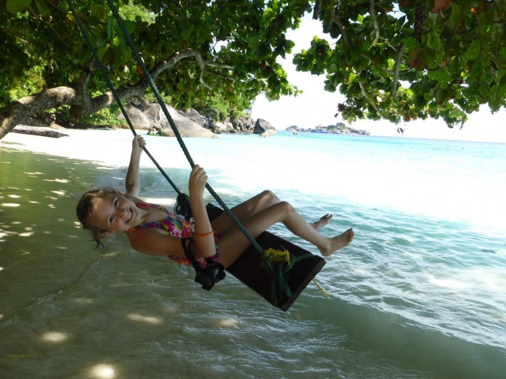 Girls swings over water on beach