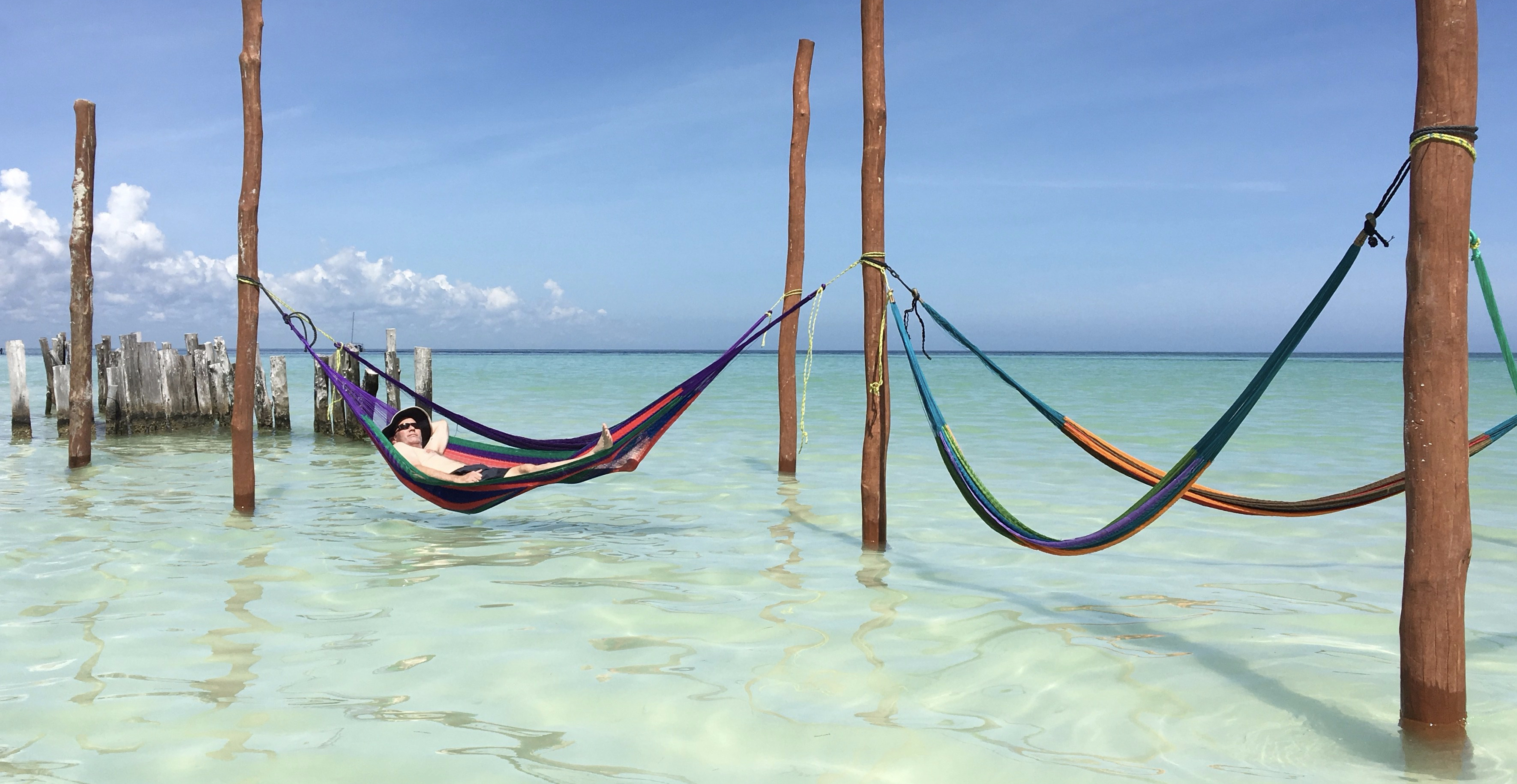 Hammocks strung over the shallow, clear ocean on Holbox Island