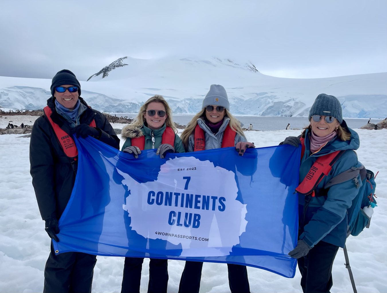The McIntyre family holding a 7 Continents Club flag in Antarctica