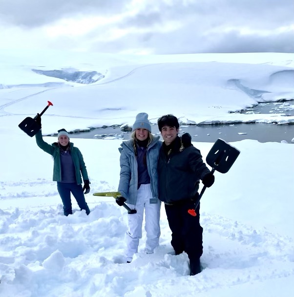 Camping in Antarctica. Three campers with snow shovels.
