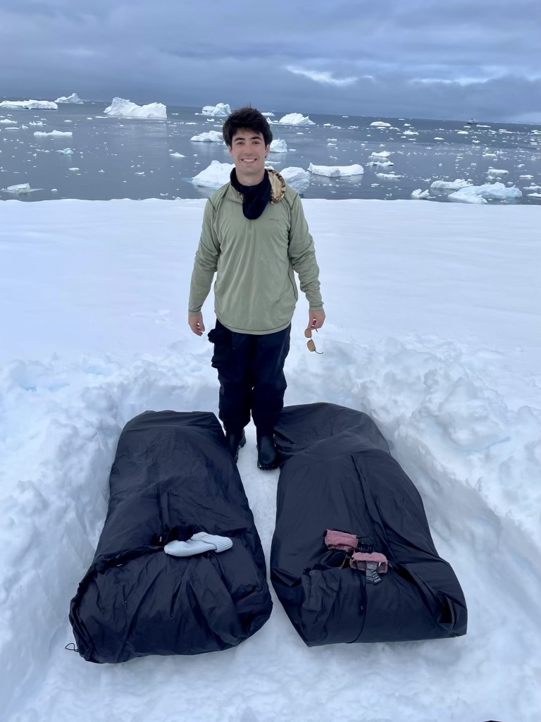 Camping in Antarctica. Man standing in front of two sleeping bags in the snow