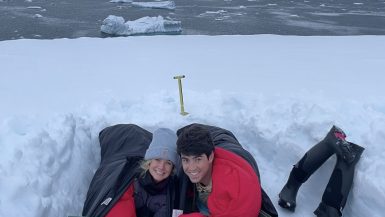 Couple in sleeping bags in snow camping in Antarctica