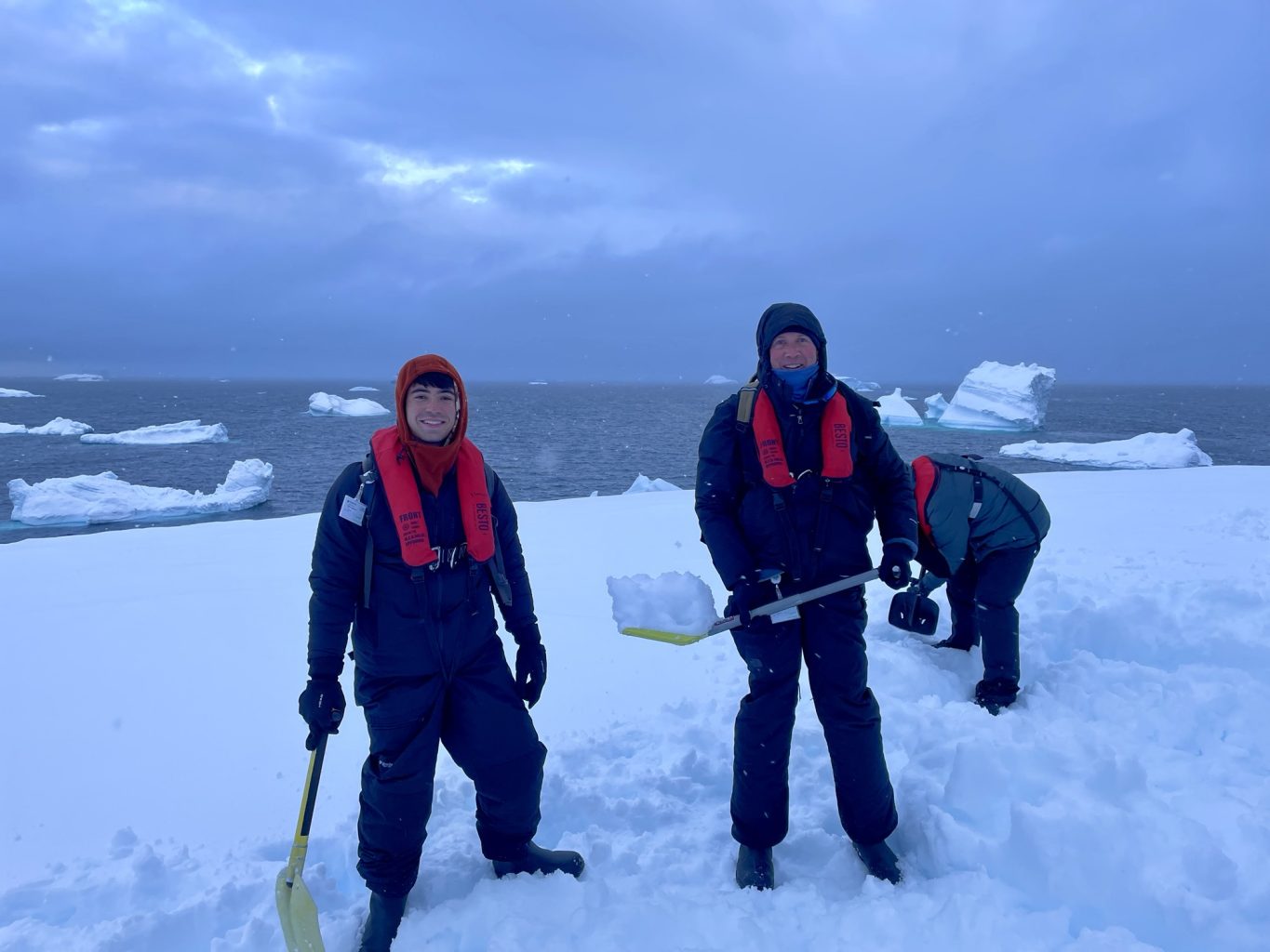 Camping in Antarctica. Two campers with snow shovels.